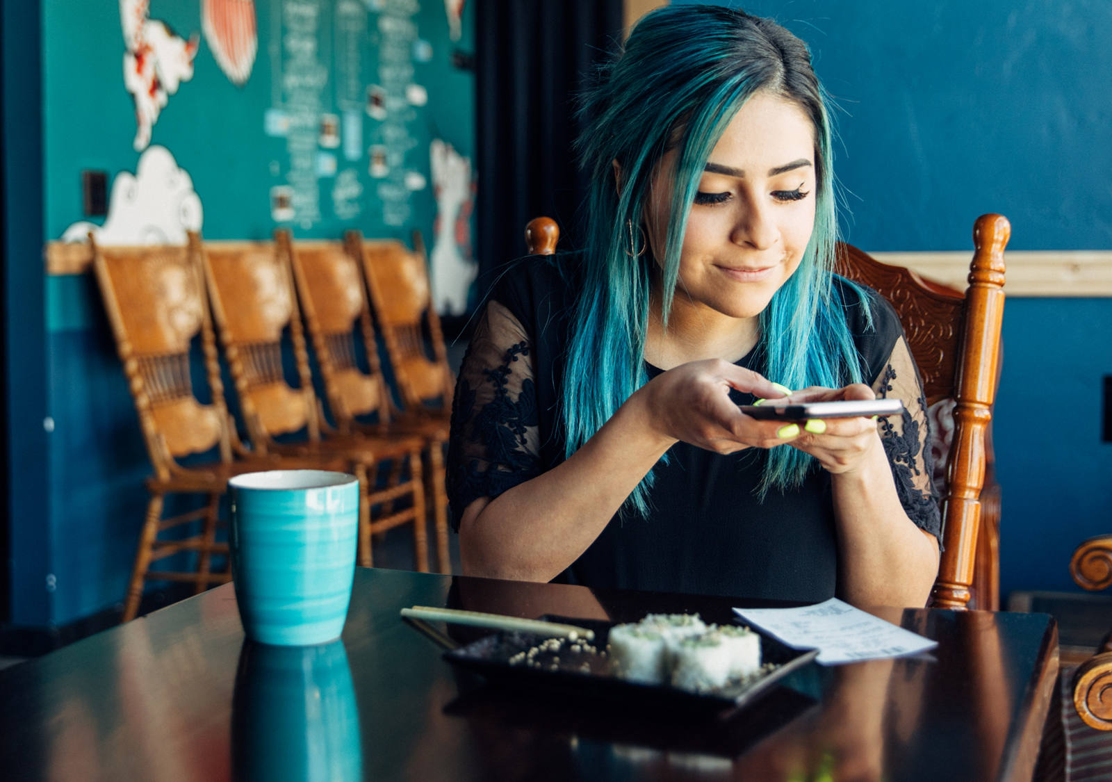 Junge Frau mit blauen Haaren fotografiert mit Smartphone eine Rechnung