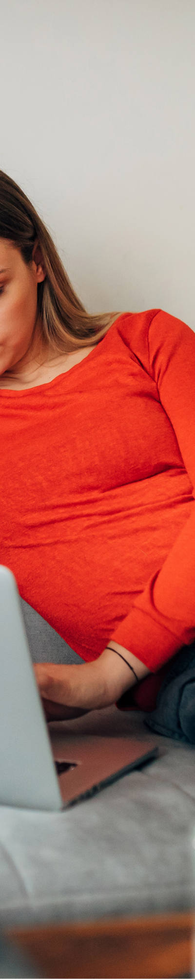 Femme travaille sur son ordinateur portable tout en étant confortablement assise sur le canapé.