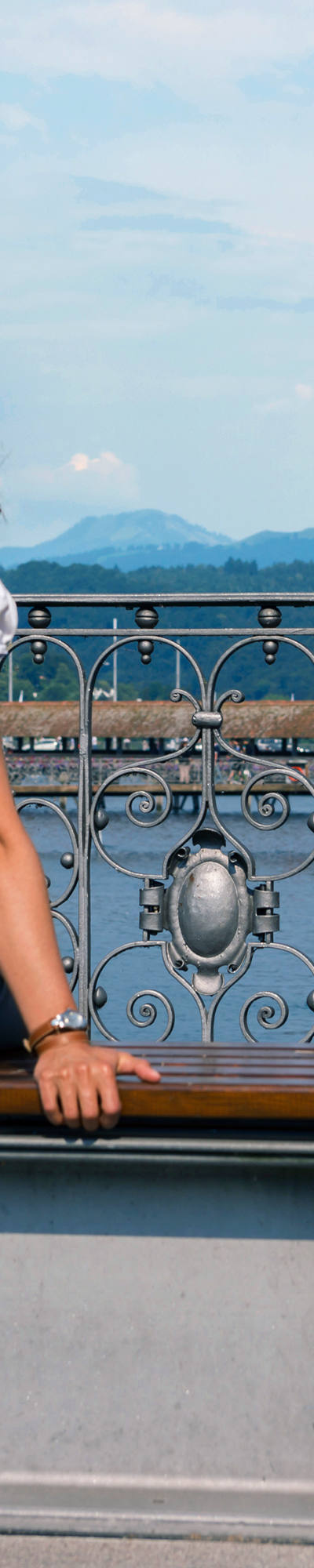 Frau sitzt auf Bank in der Stadt Luzern und blickt auf Wasserturm und Kappelbrücke