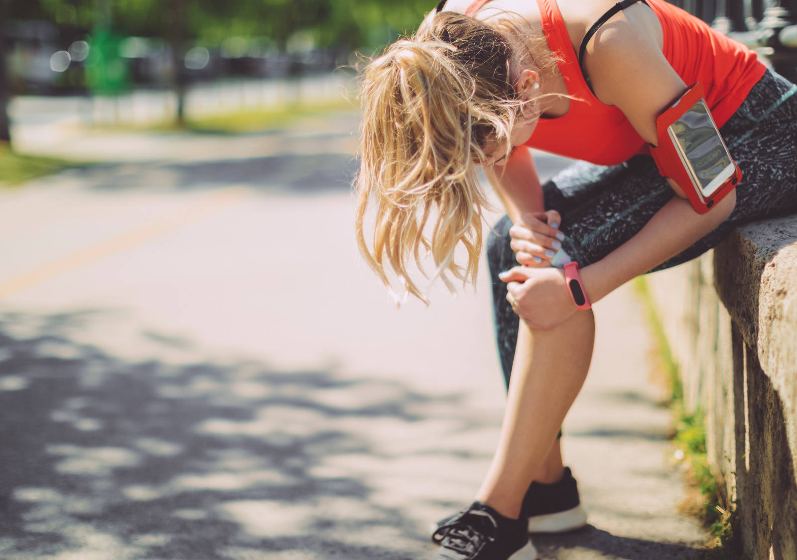 Frau macht eine Jogging Pause und hält sich das Knie.