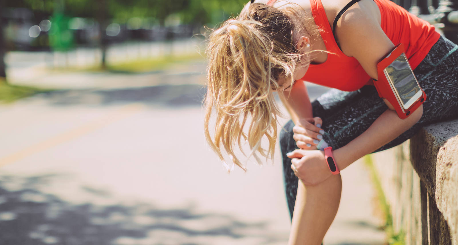Frau macht eine Jogging Pause und hält sich das Knie.