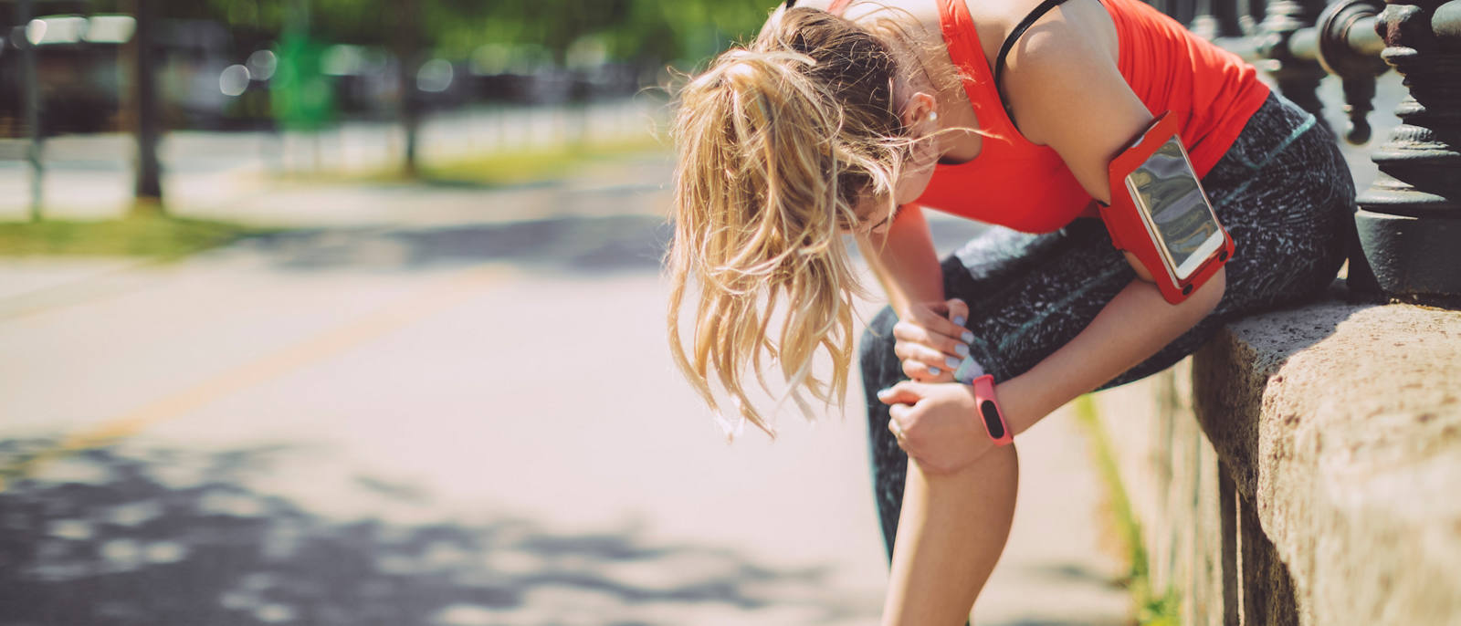 Frau macht eine Jogging Pause und hält sich das Knie.