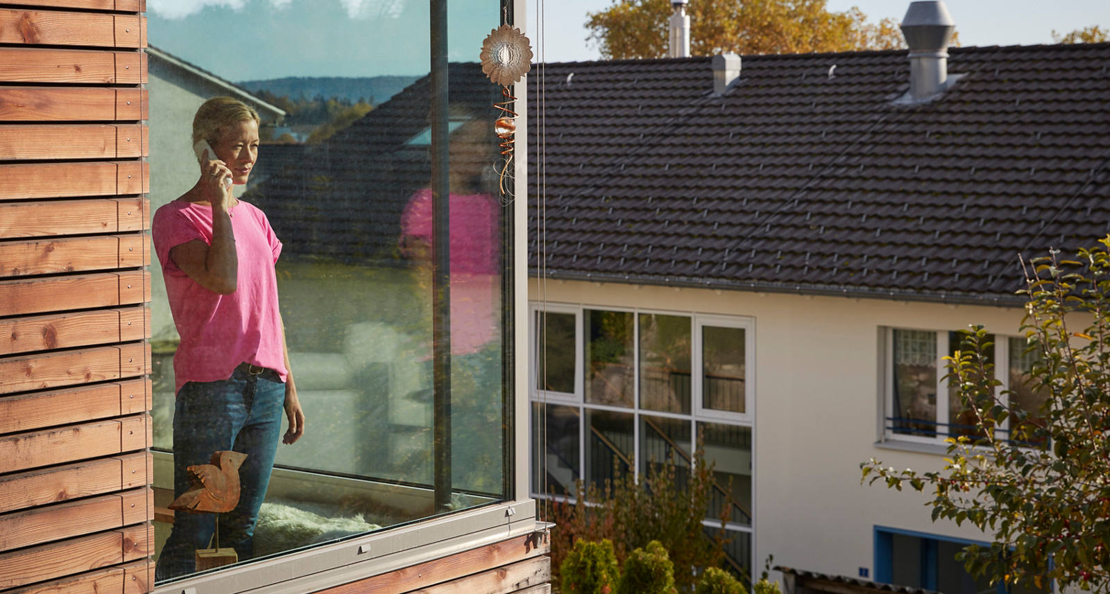  Une femme se tient devant une grande fenêtre et passe un appel téléphonique.