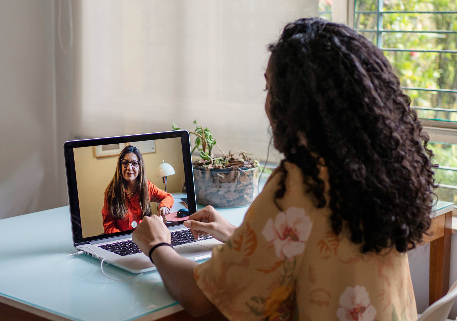 Woman sits at the table with her laptop and has a digital therapy session.