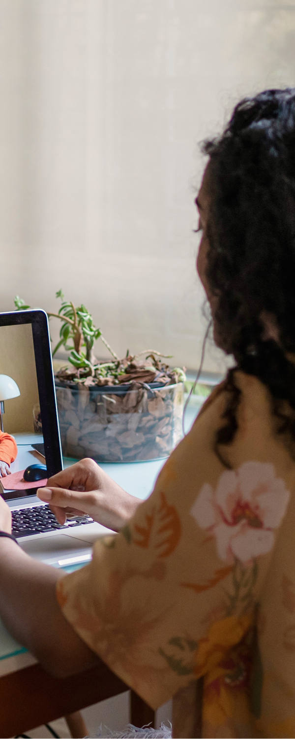 Woman sits at the table with her laptop and has a digital therapy session.