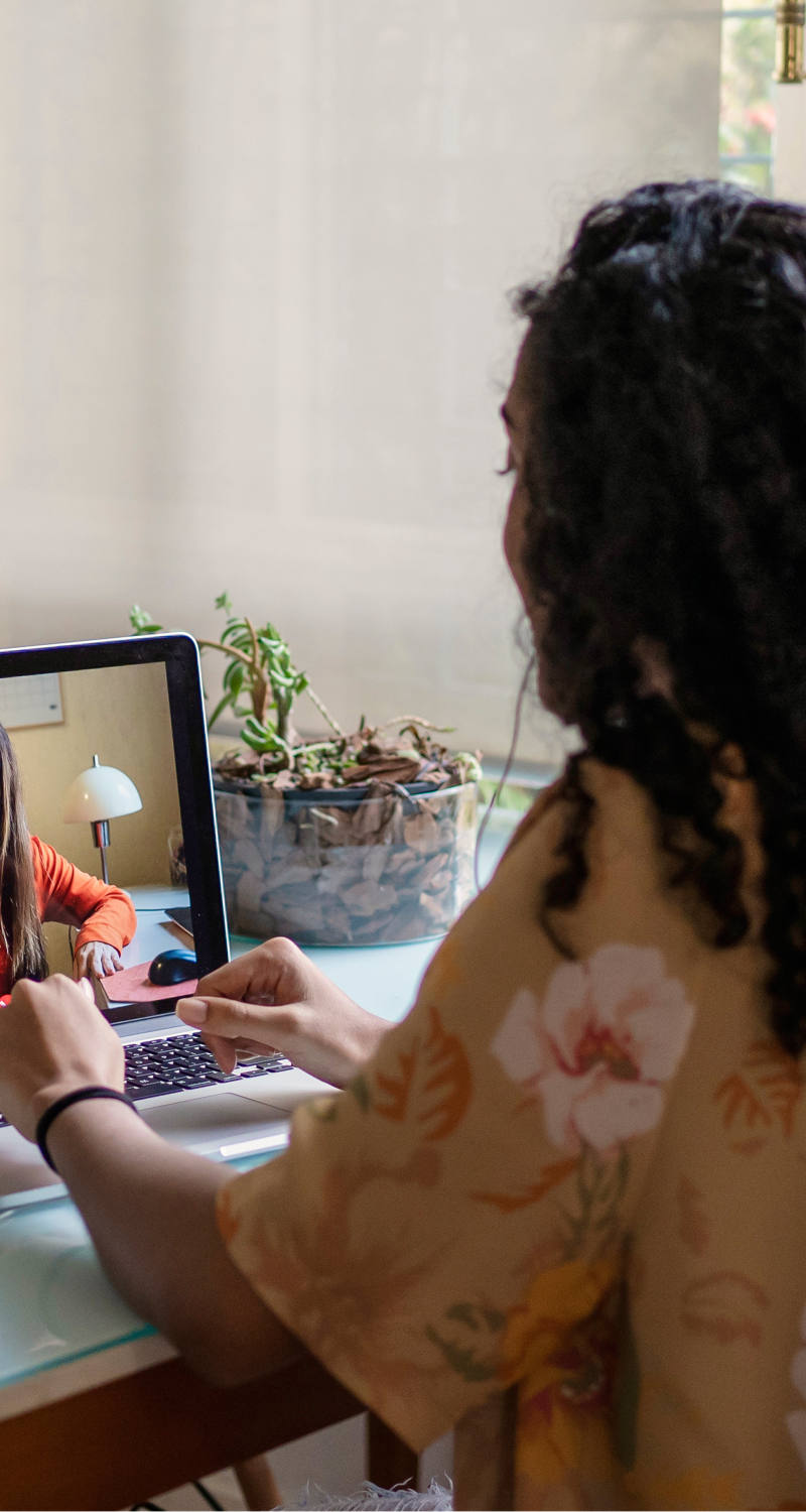 Woman sits at the table with her laptop and has a digital therapy session.