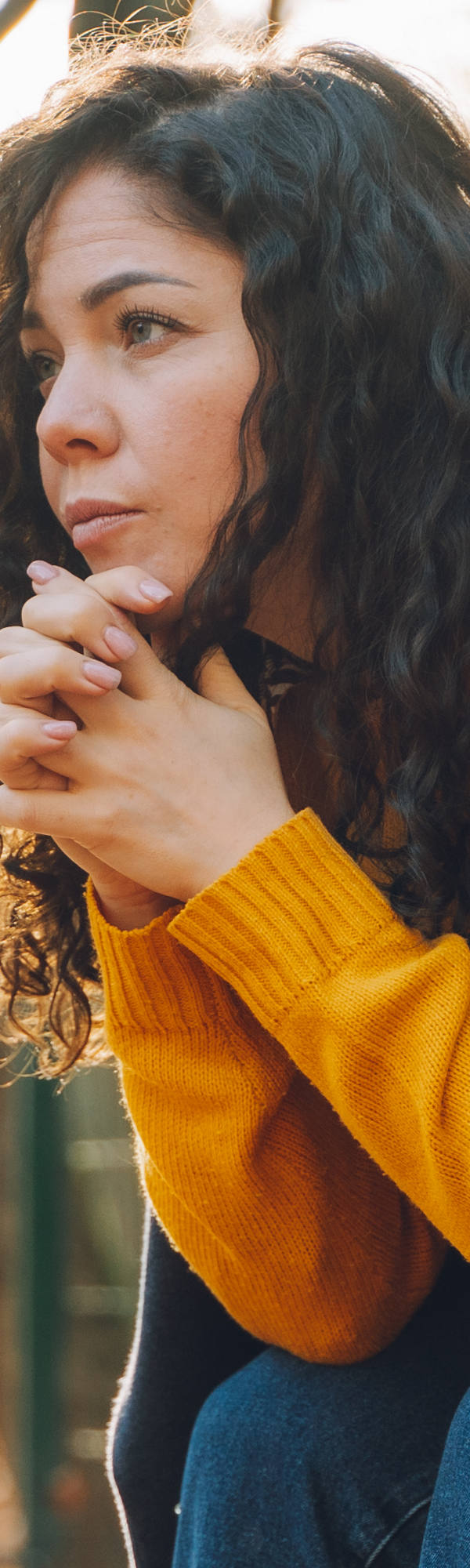  A woman sits sadly on a bench in the park.