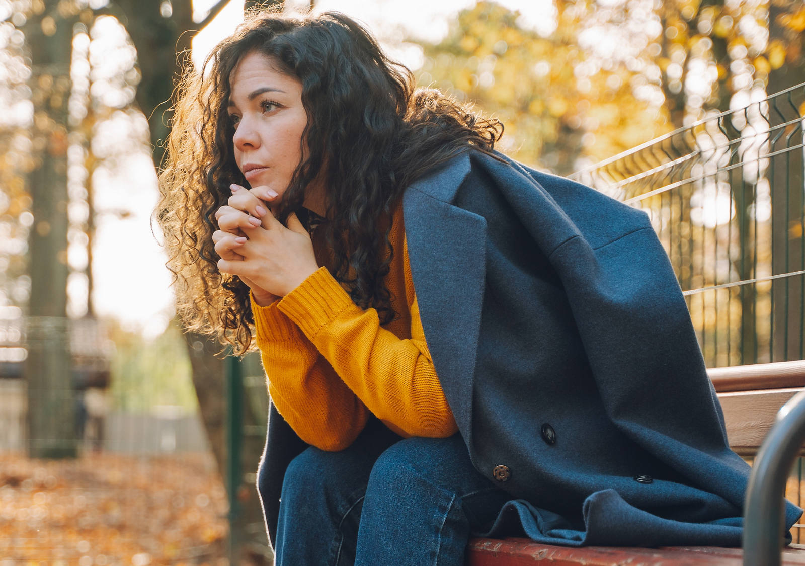 Una donna è seduta triste su una panchina nel parco.