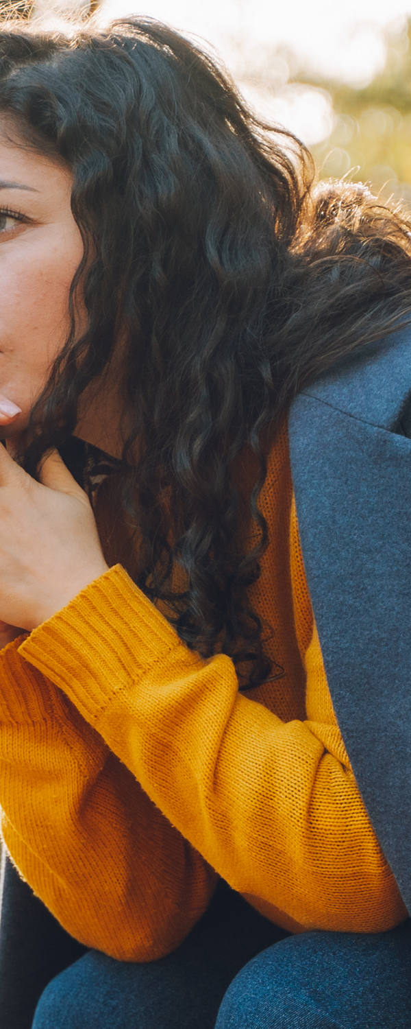 Una donna è seduta triste su una panchina nel parco.