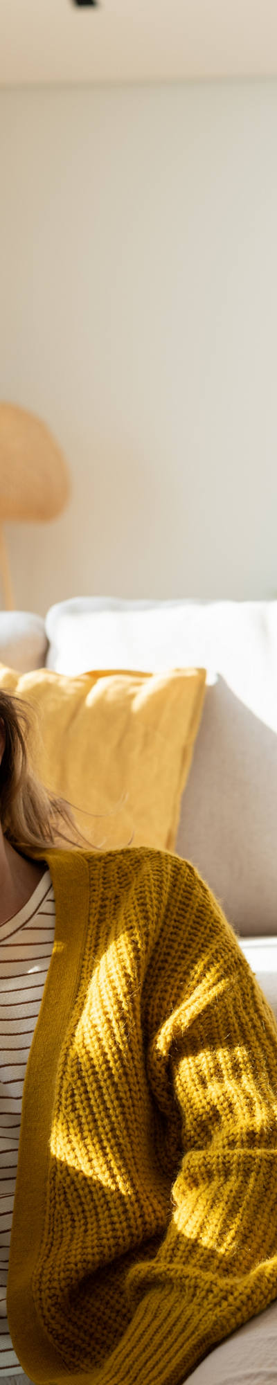 Une femme fatiguée est assise par terre devant un canapé et se serre son front épuisée.