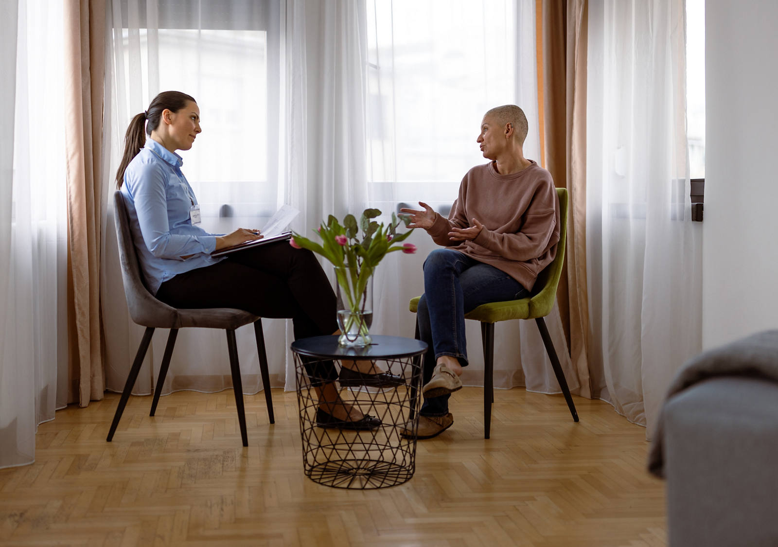 Deux femmes sont assises dans une salle de consultation. La patiente atteinte d’un cancer reçoit un soutien psychologique.