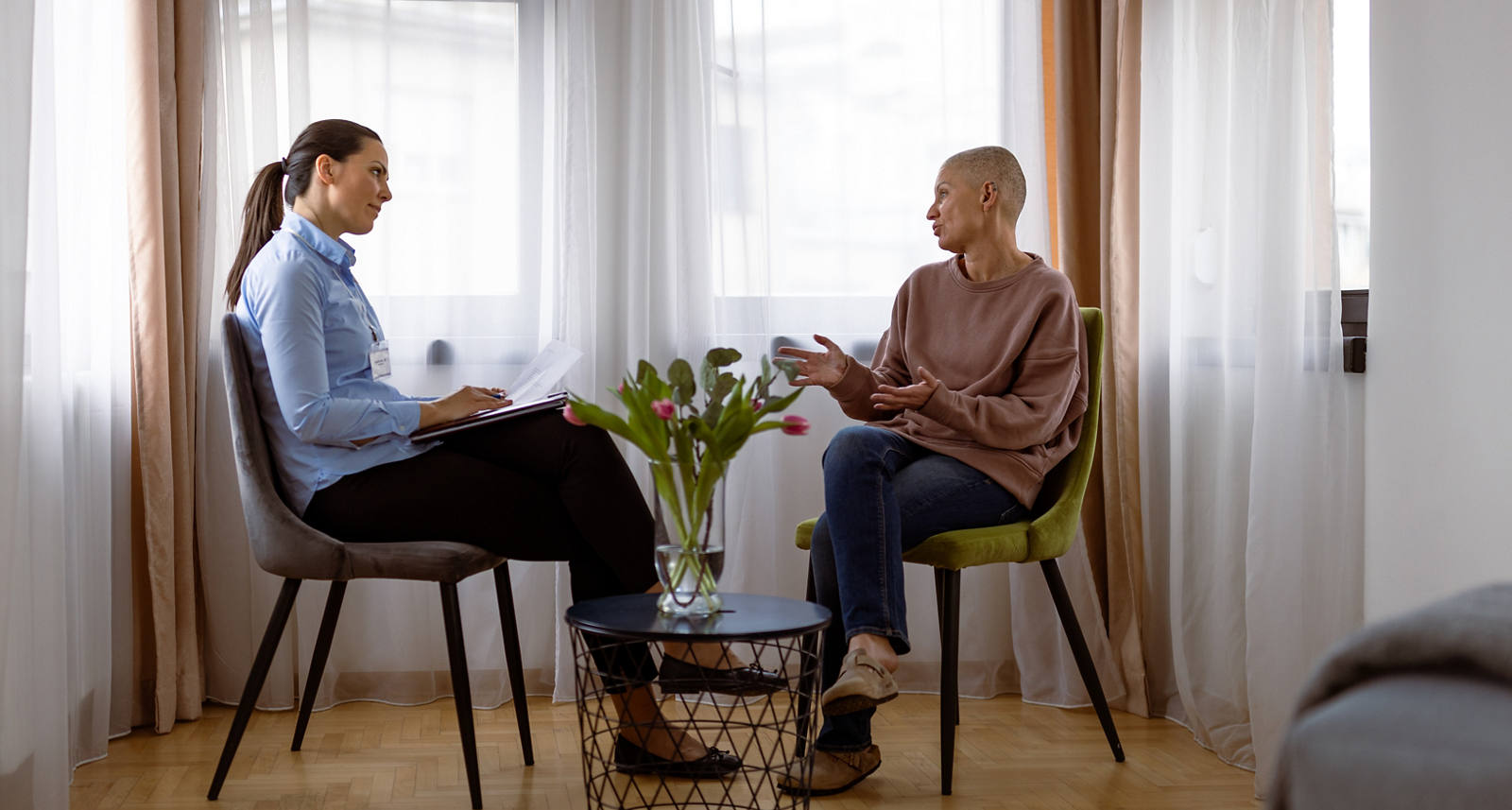 Deux femmes sont assises dans une salle de consultation. La patiente atteinte d’un cancer reçoit un soutien psychologique.