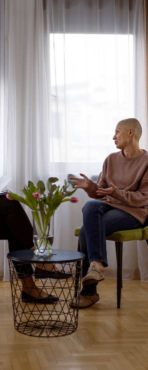 Two women are sitting in a meeting room. The cancer patient receives emotional support.