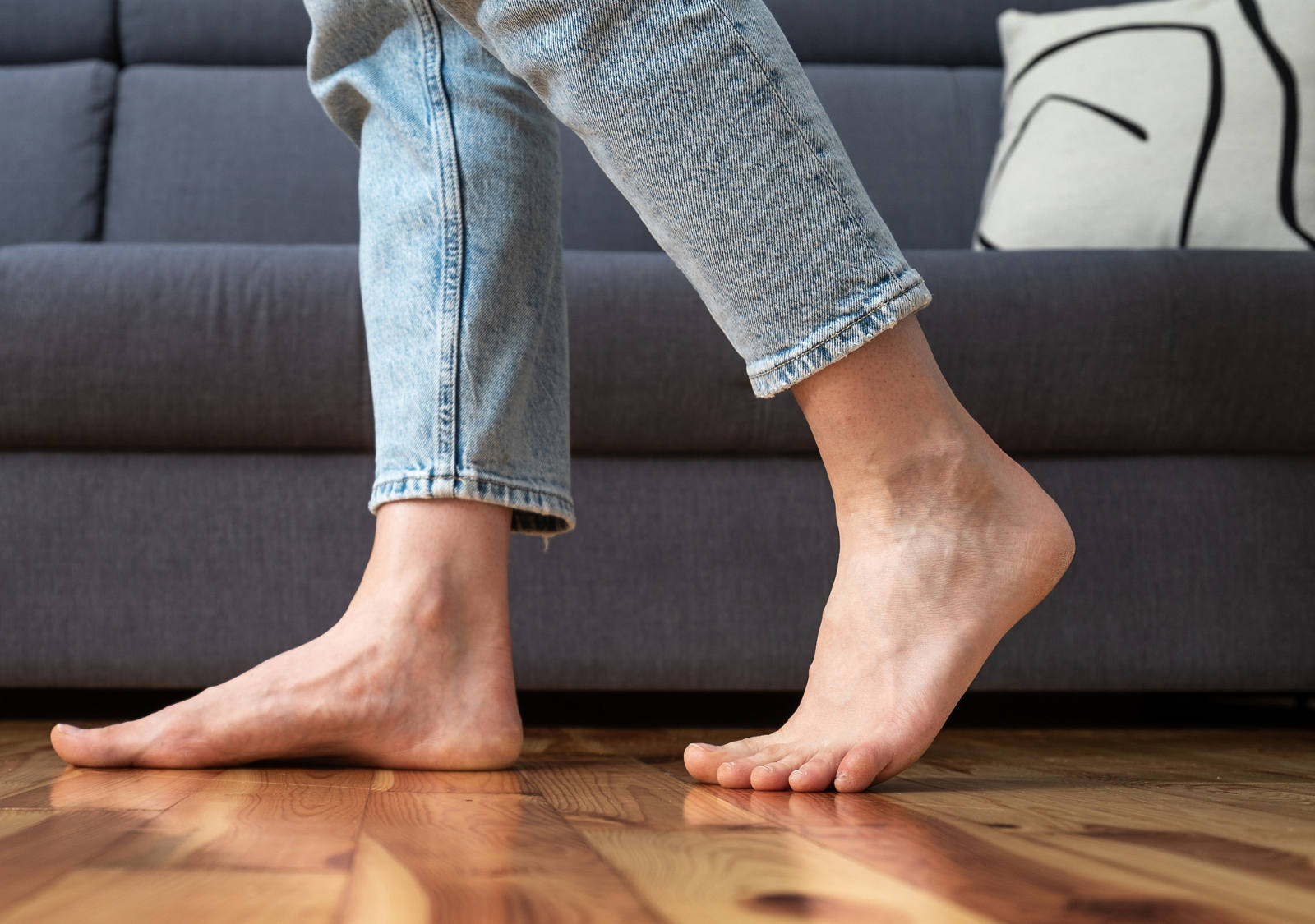 A woman walks barefoot in the living room on the wooden floor.