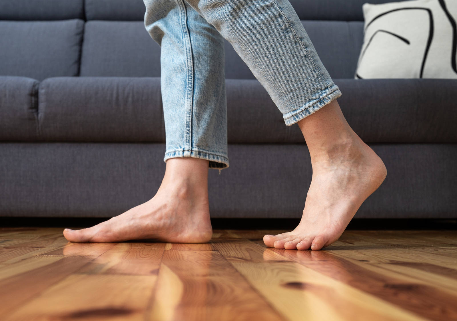 A woman walks barefoot in the living room on the wooden floor.