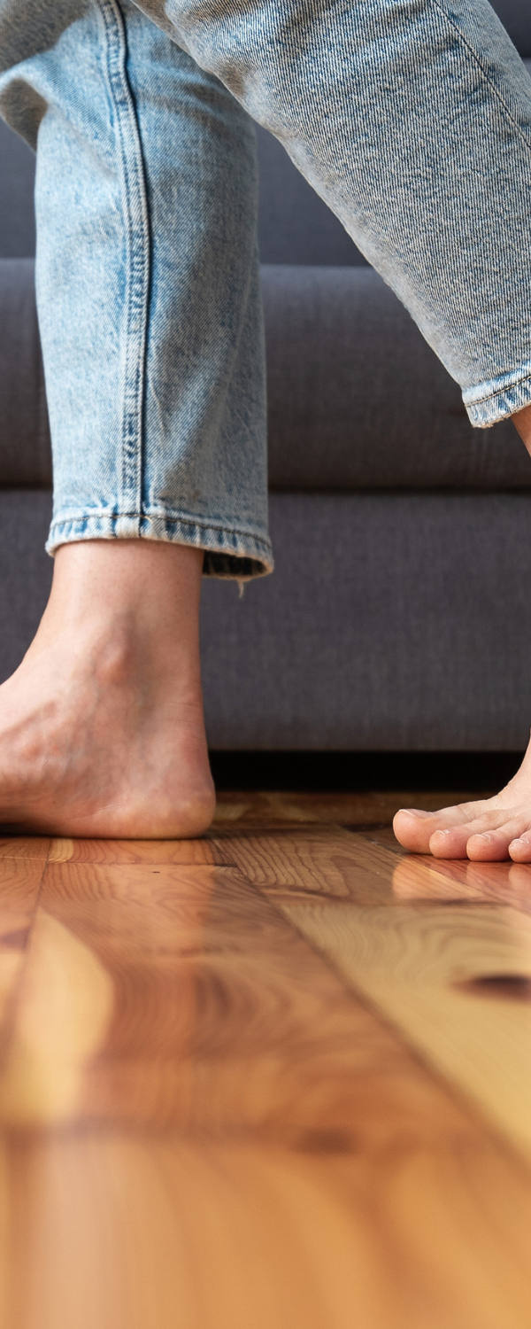 A woman walks barefoot in the living room on the wooden floor.