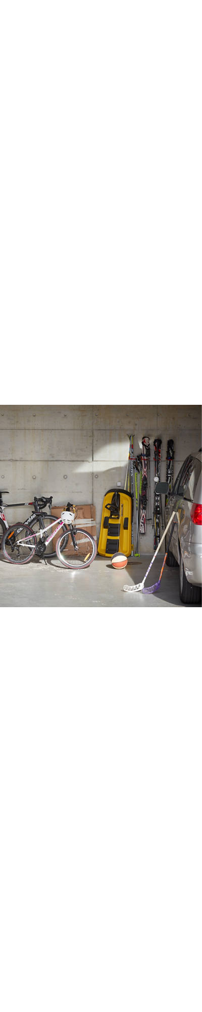 Fahrräder stehen neben dem Auto und anderen Sport-Utensilien in der Garage.