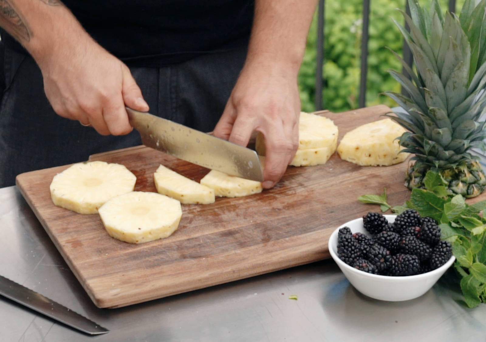 Mann schneidet Ananas in mittelgrosse Streifen