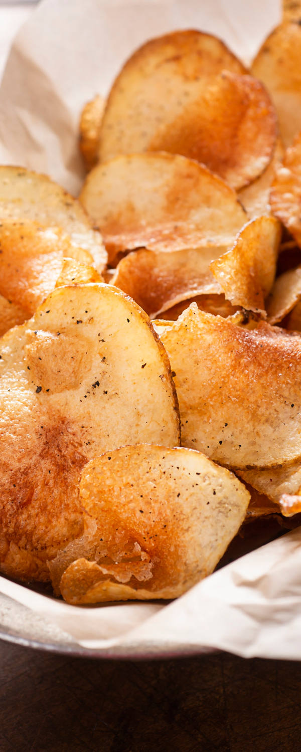 Auf einem Tisch ist eine Portion Salz-Chips in einer Schüssel angerichtet.