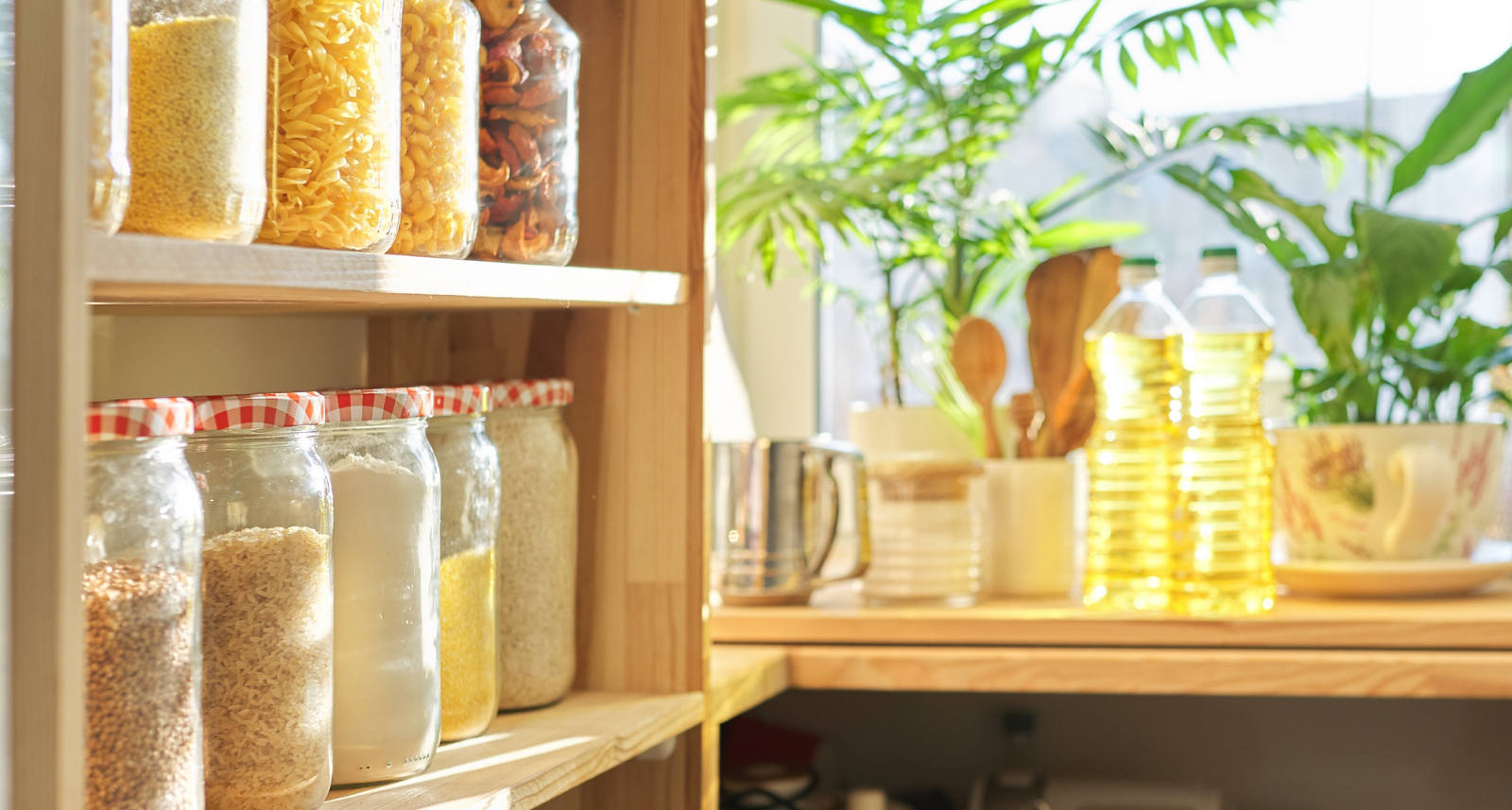 On a kitchen shelf there are lots of assorted preserving jars. They are filled with all sorts of things.