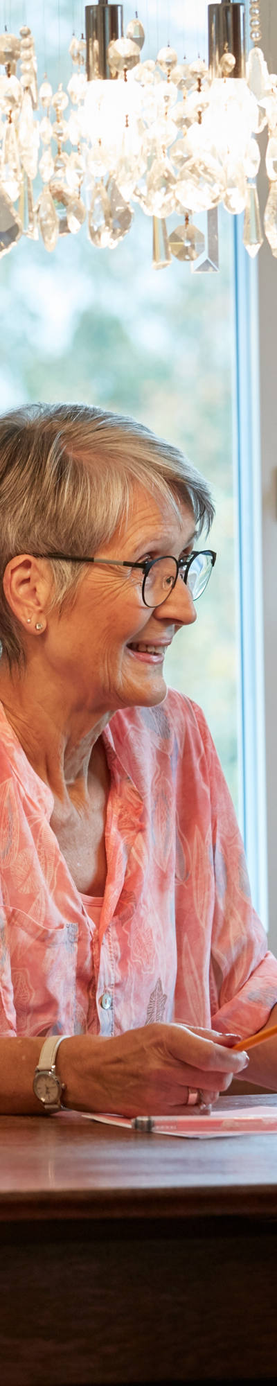 Grand-mère est assise à une table et prend une tablette.
