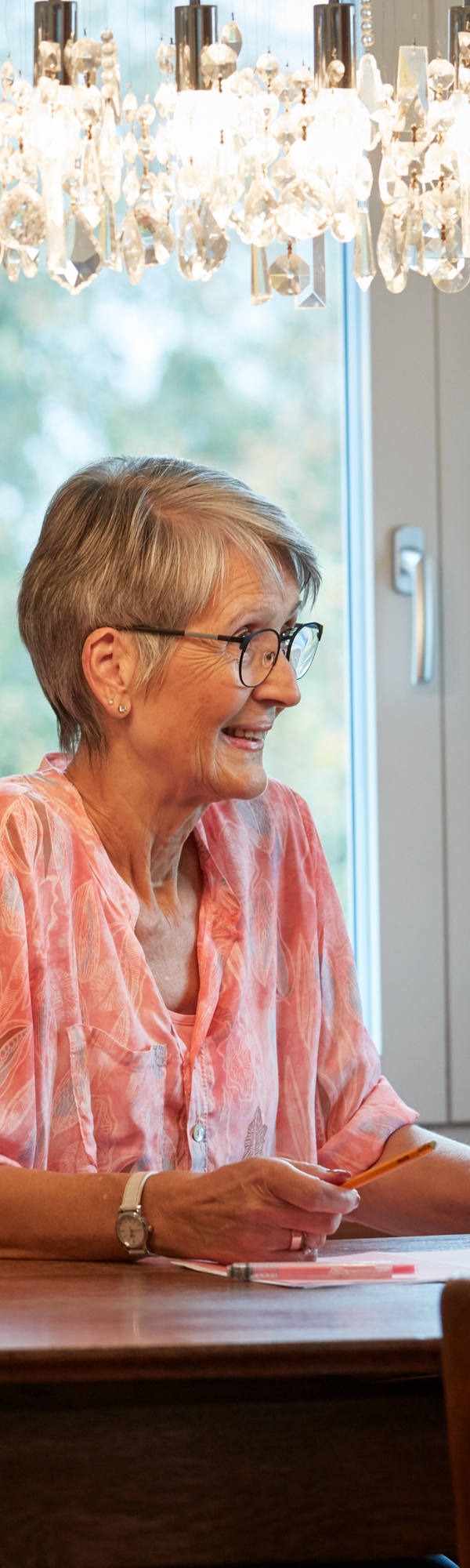 Grossmutter sitzt am Tisch und ist am Tablet.