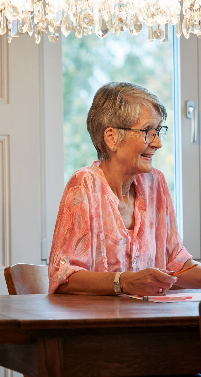 Grand-mère est assise à une table et prend une tablette.