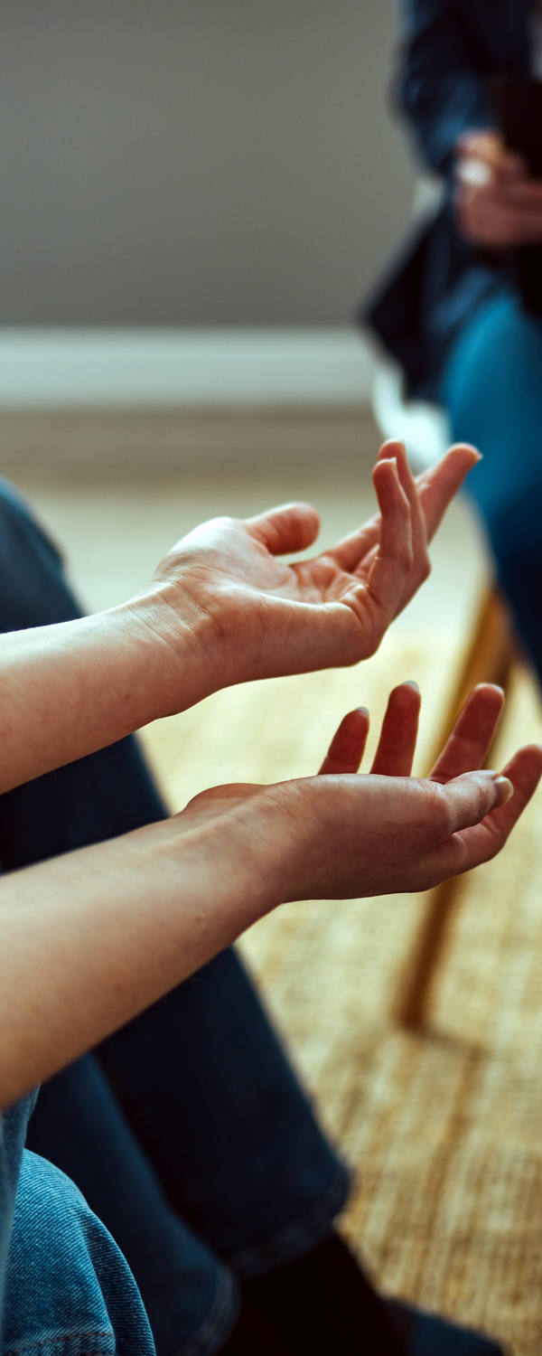 A group of people is sitting in a circle, with the focus on the woman's hands.