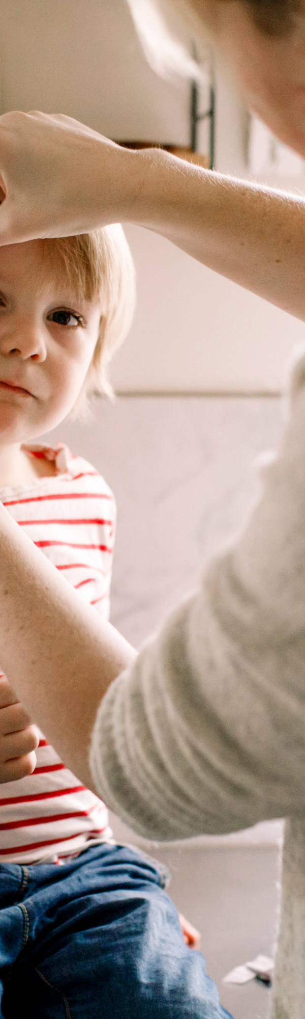 Mutter verarztet Kind mit einem Pflaster an der Augsbraue.