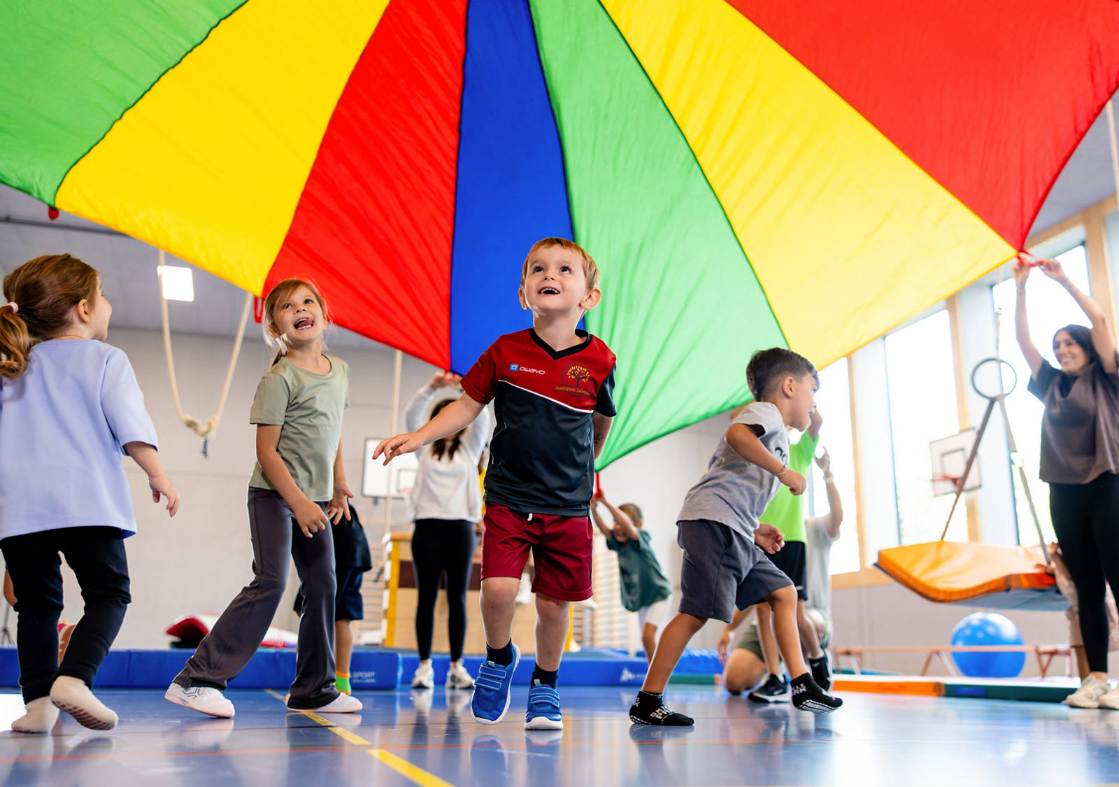 Kinder spielen gemeinsam in der Turnhalle, bewegen sich und haben Spass.