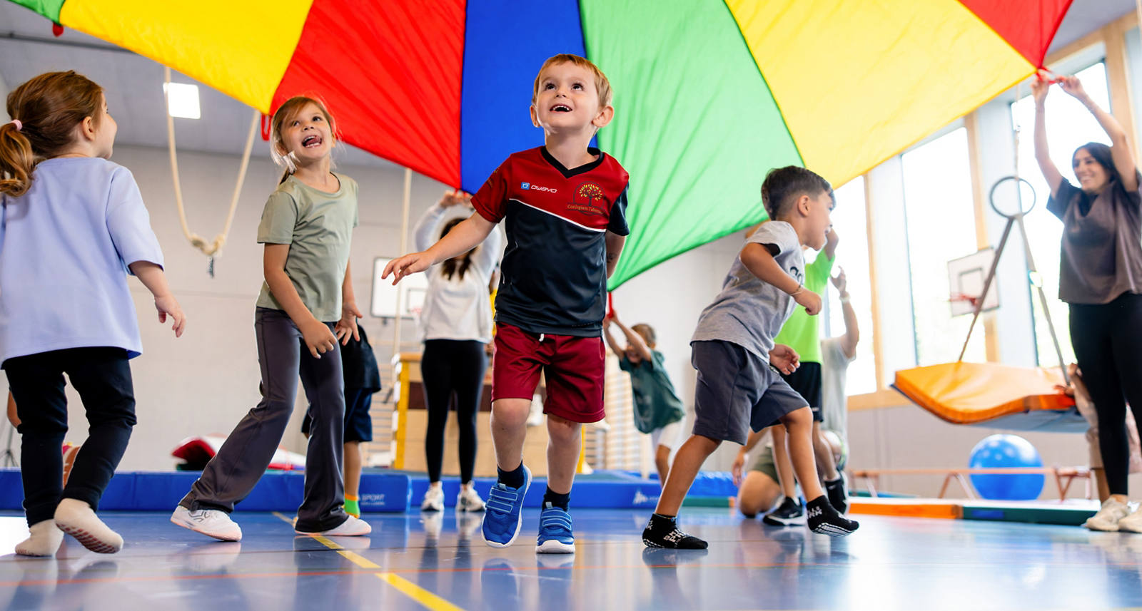 Kinder spielen gemeinsam in der Turnhalle, bewegen sich und haben Spass.