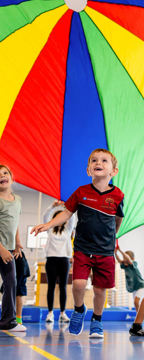 Kinder spielen gemeinsam in der Turnhalle, bewegen sich und haben Spass.