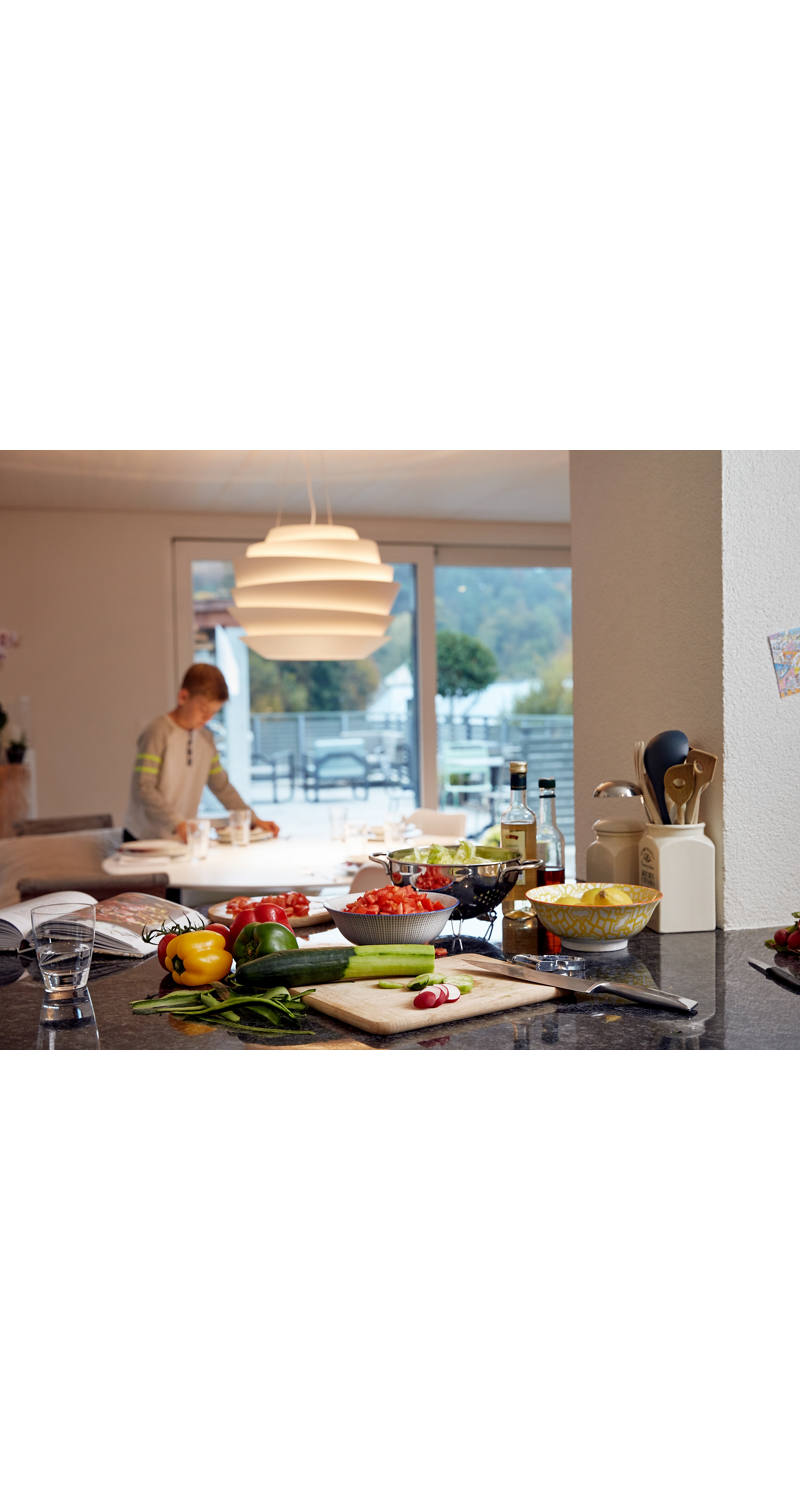 In the kitchen, vegetables are chopped and the table is set.