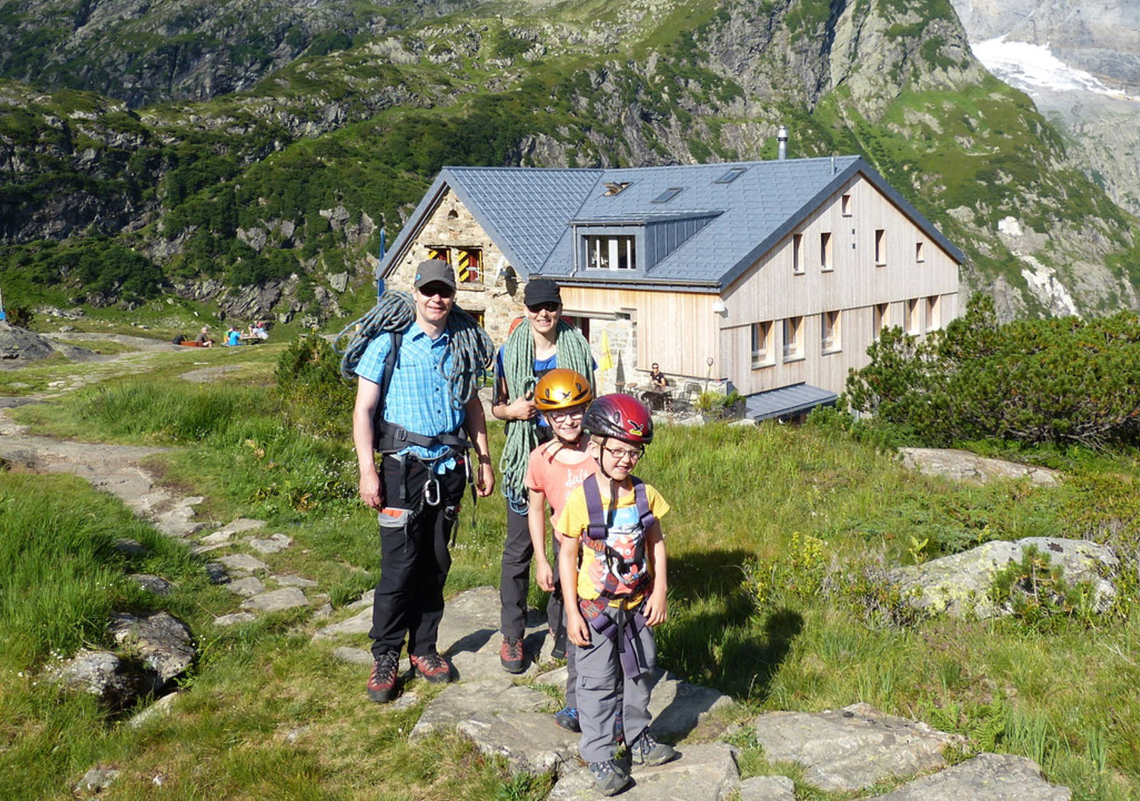 Eine Familie posiert vor der Kröntenhütte bei Sonnenschein.