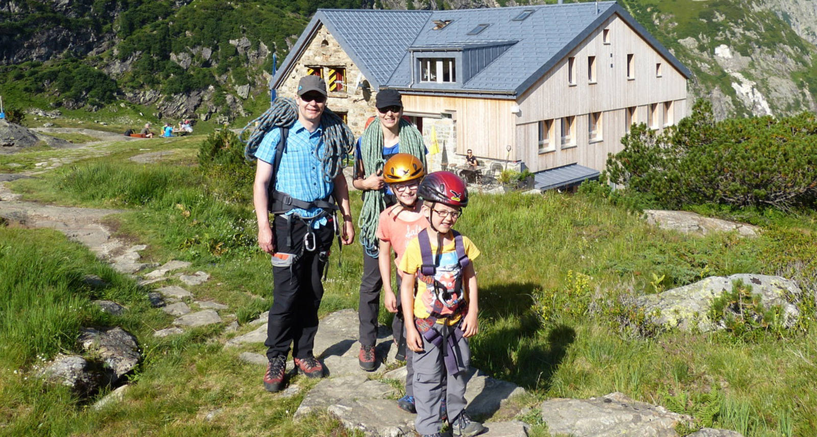 Eine Familie posiert vor der Kröntenhütte bei Sonnenschein.