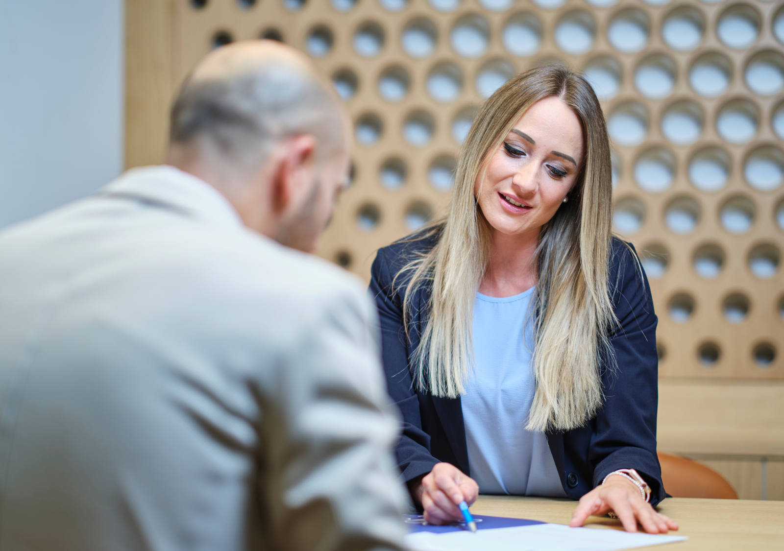 Un uomo viene consigliato da una donna a un tavolo di legno con penna e carta.
