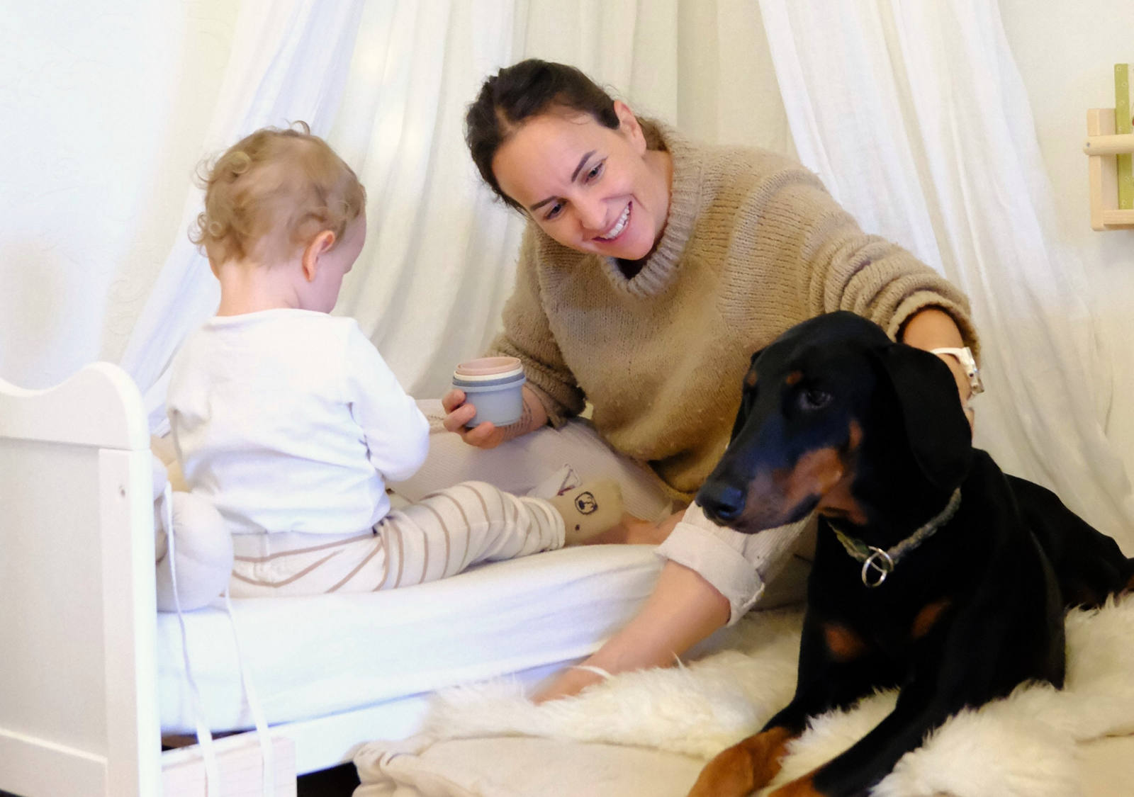 CSS Mitarbeiterin Laura Pasula mit ihrem Sohn Ando und der Dobermann-Hündin Luma glücklich im Kinderzimmer am spielen.