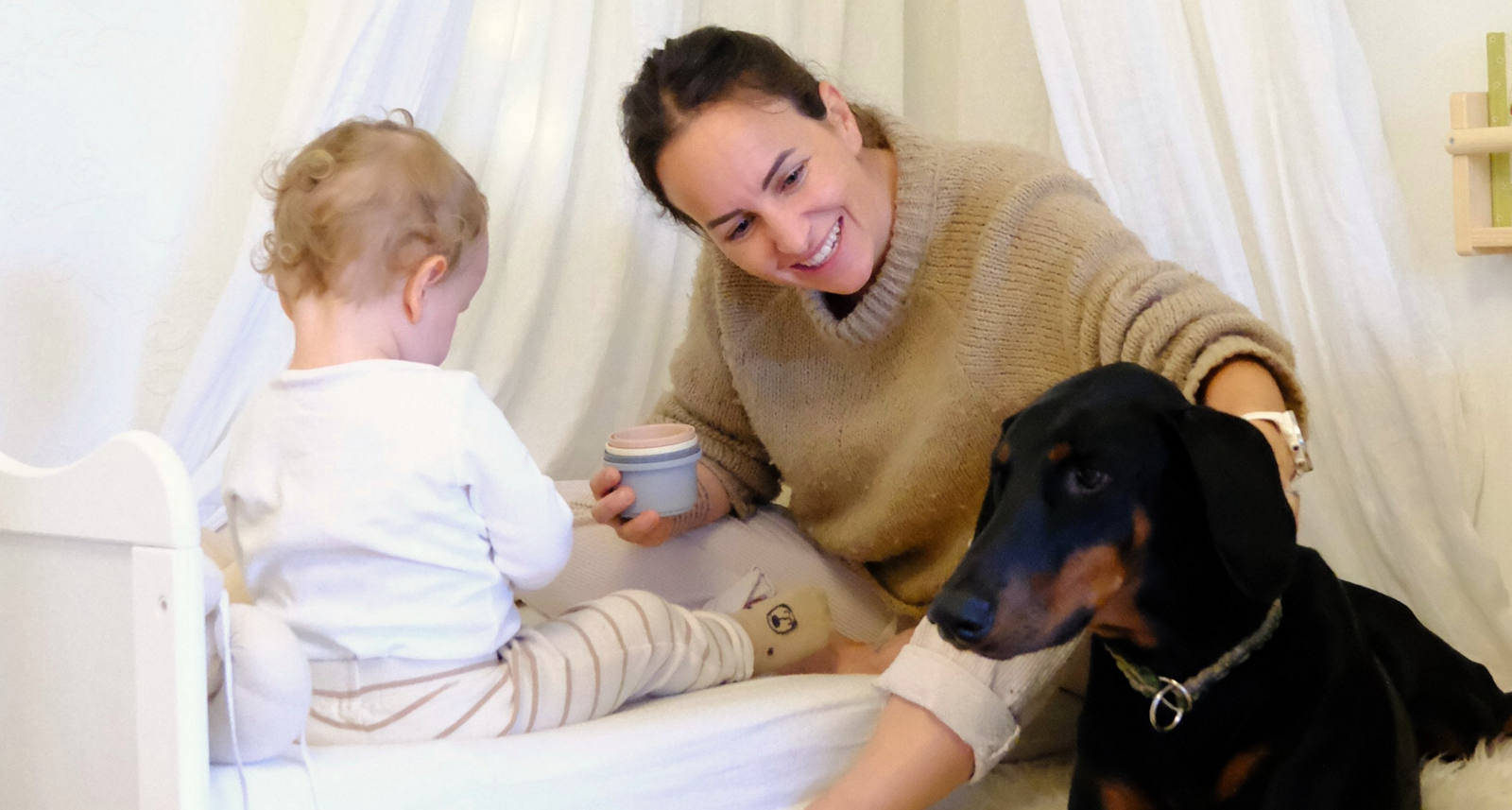 CSS Mitarbeiterin Laura Pasula mit ihrem Sohn Ando und der Dobermann-Hündin Luma glücklich im Kinderzimmer am spielen.