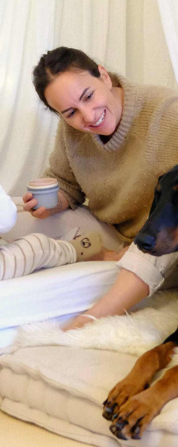 CSS Mitarbeiterin Laura Pasula mit ihrem Sohn Ando und der Dobermann-Hündin Luma glücklich im Kinderzimmer am spielen.