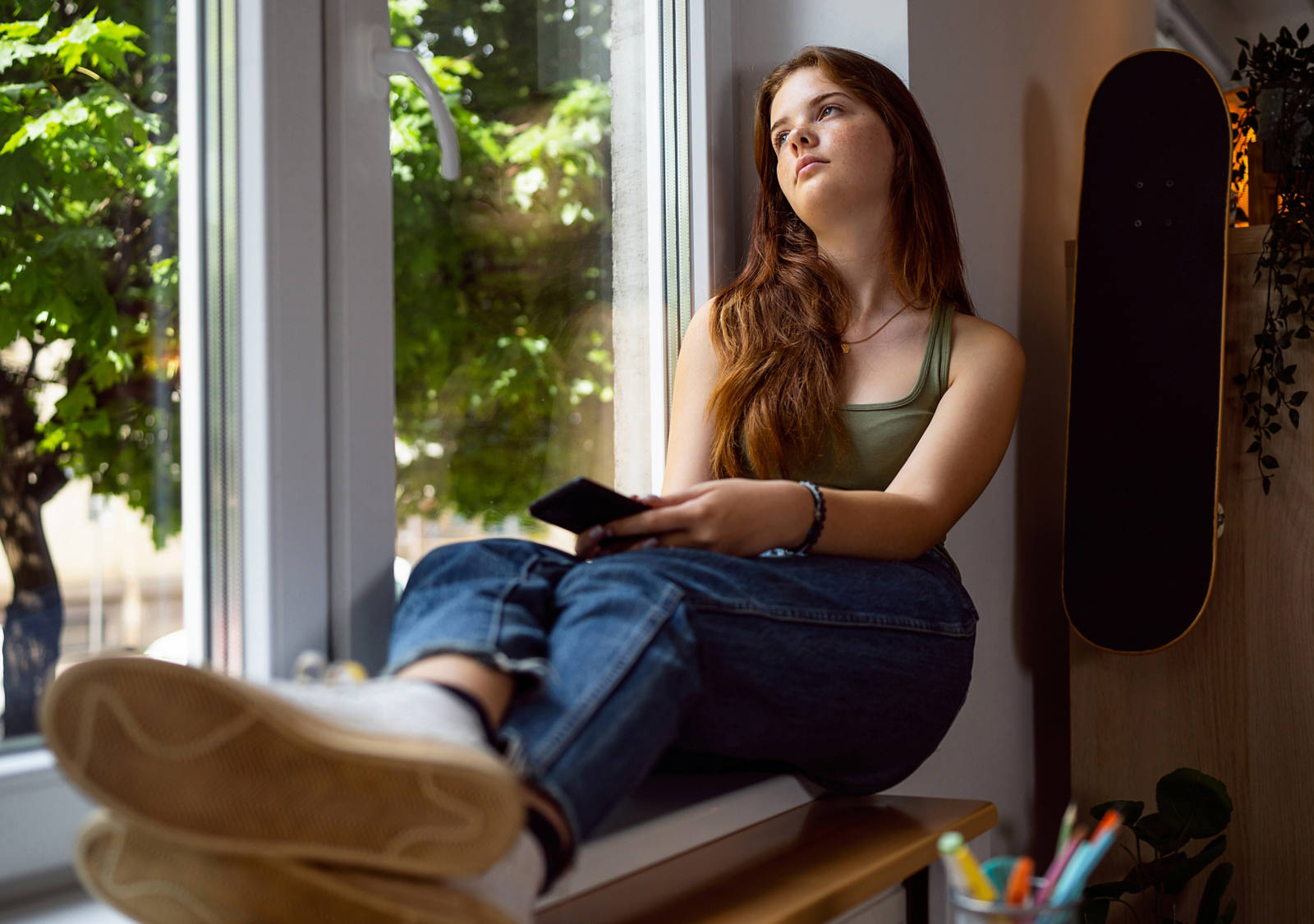 Eine junge Frau sitzt am Fenster und schaut traurig