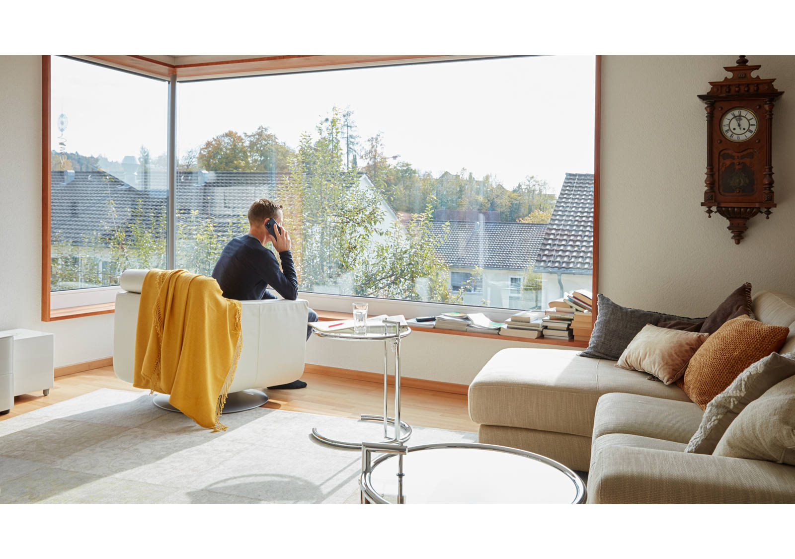 Mann sitzt in Sofastuhl im Wohnzimmer und telefoniert