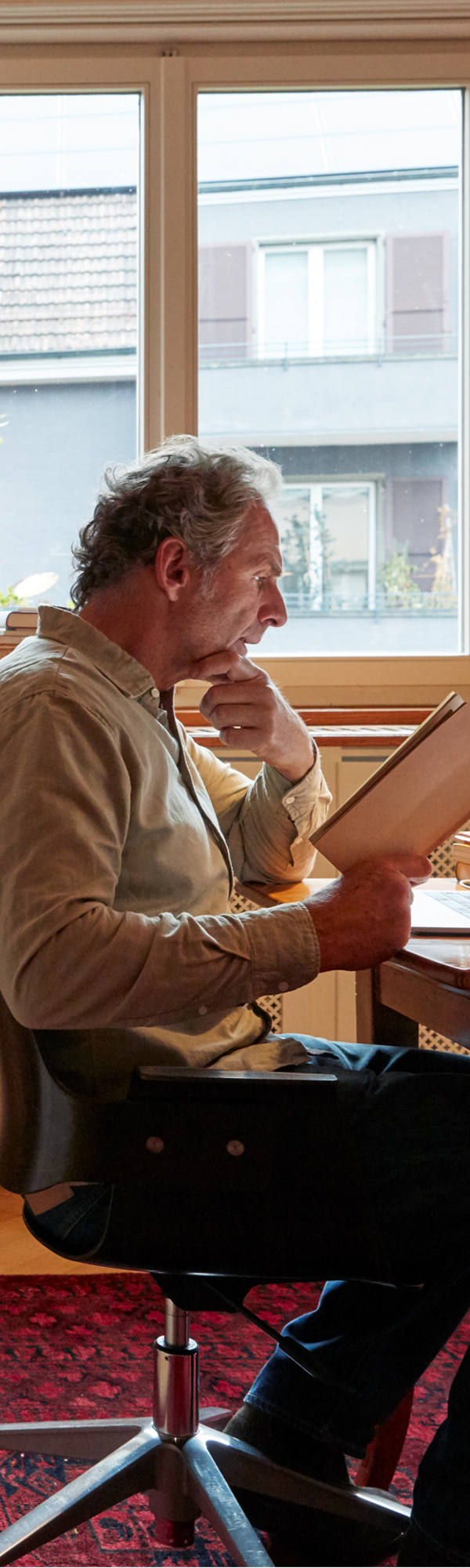 Homme étudie le livre dans son bureau à la maison. En arrière-plan se trouve un immense mur de livres.