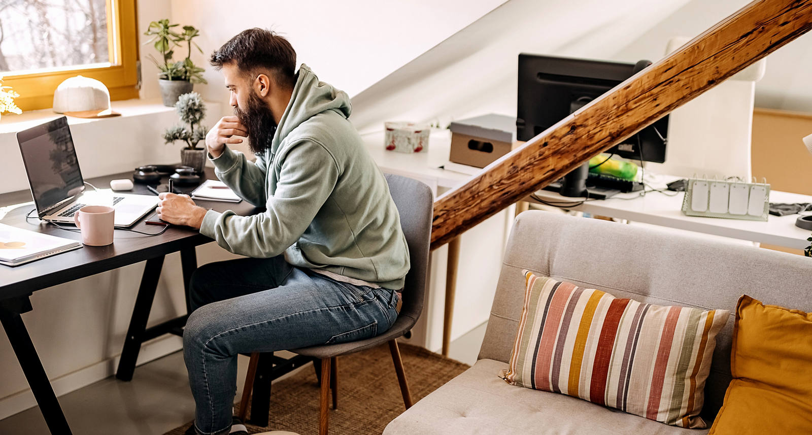Giovane lavora alla scrivania di casa mentre il suo cane dorme ai suoi piedi
