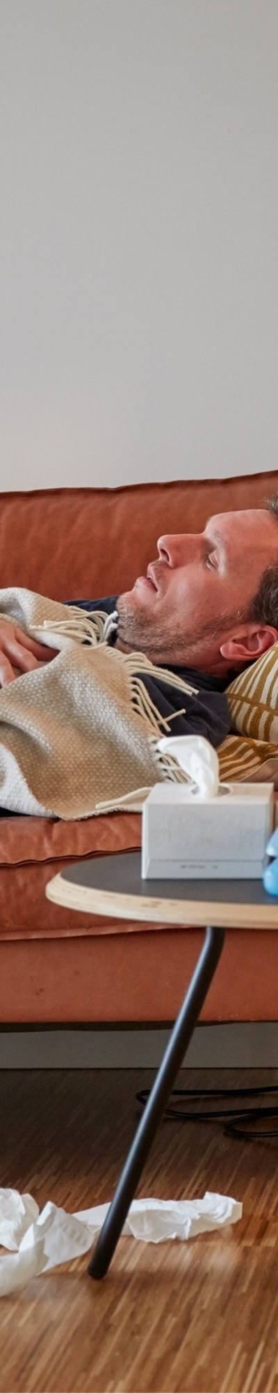 Mann liegt krank auf dem Sofa