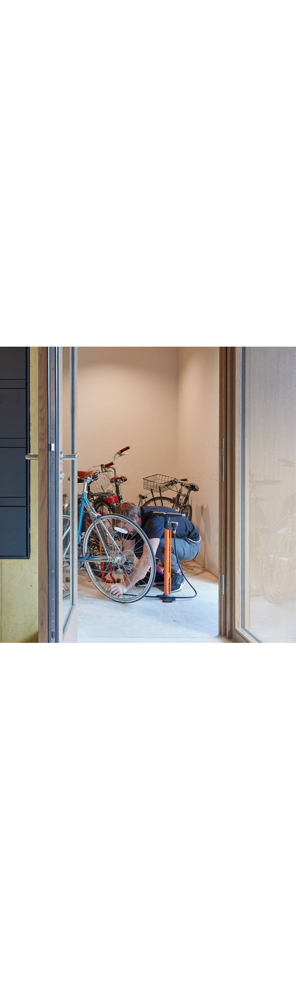 Mann pumpt Fahrraddreifen im Eingang eines Mehrfamilienhauses