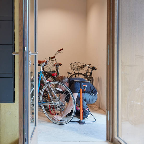 Mann pumpt Fahrraddreifen im Eingang eines Mehrfamilienhauses