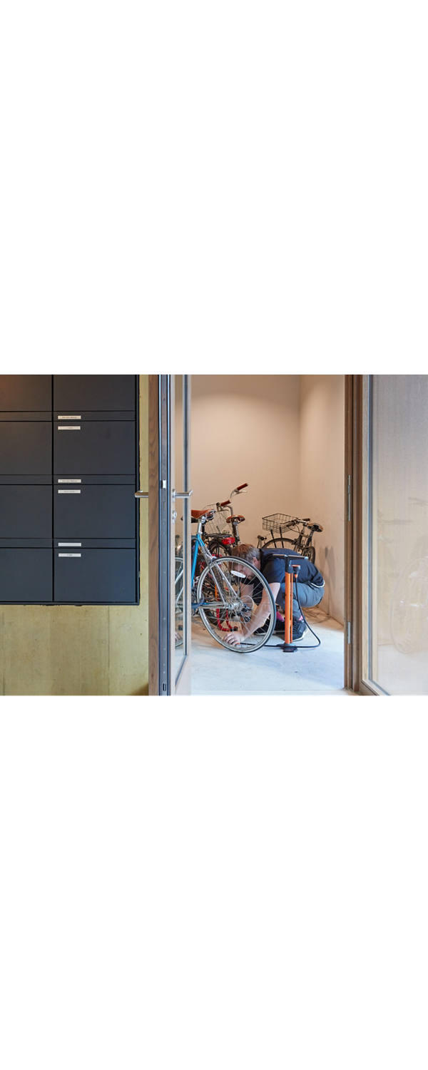 Mann pumpt Fahrraddreifen im Eingang eines Mehrfamilienhauses