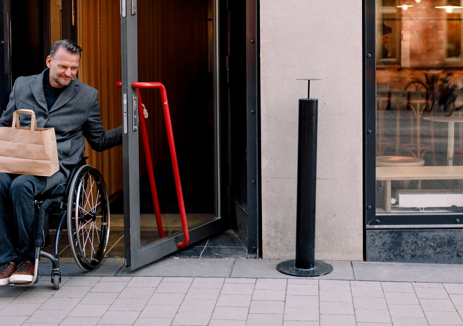  Better writing: A man in a wheelchair leaves a coffee through the door.