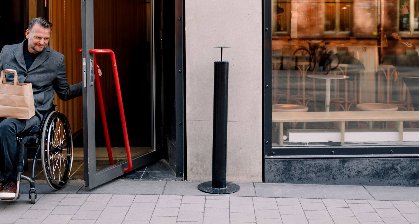  Better writing: A man in a wheelchair leaves a coffee through the door.
