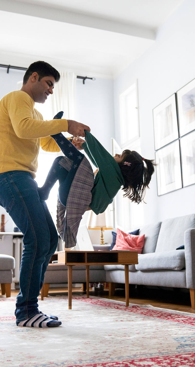 Father playing with daughter in living room